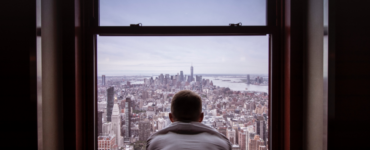 man looking outside of window for mental health